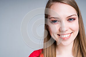 Portrait of a happy girl with long hair smiling broadly showing snow-white teeth and looking at the camera photo