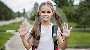 Portrait of happy girl with school bag standing outdoor. Little happy school girl going to school, back to school, education