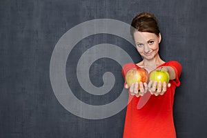 Portrait of happy girl smiling and offering to taste ripe apples