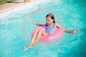 Portrait of happy girl swimming on inflatable ring in pool