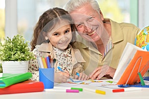 Portrait of happy grandfather with granddaughter drawing together