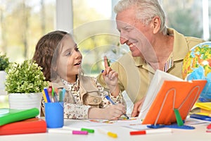 Portrait of happy grandfather with granddaughter drawing together
