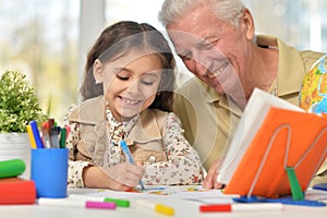 Portrait of happy grandfather with granddaughter drawing together