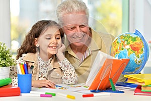 Portrait of happy grandfather with granddaughter drawing together