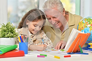 Portrait of happy grandfather with granddaughter drawing together