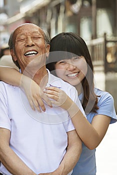 Portrait of happy grandfather and granddaughter together, outdoors in Beijing