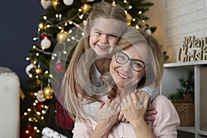 Portrait of happy grandmother and granddaughter embracing in Christmas time