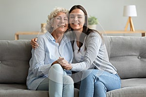 Portrait happy grandmother and granddaughter hugging, sitting on couch