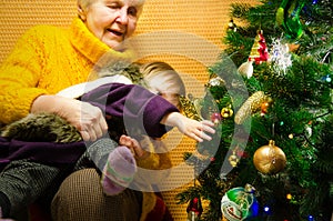 Portrait of happy grandmother hugging her granddaughter over Christmas presents and decorated New Year tree, merry