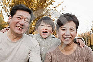 Portrait of Happy Grandparents and Grandson in the Park in Autumn