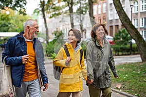 Portrait of happy grandparents with preteen grandddaughter walking together ourtdoors in town street