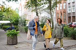 Portrait of happy grandparents with preteen grandddaughter walking together ourtdoors in town street