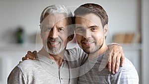 Portrait of happy grownup son hug elderly 70s dad