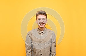 Portrait of happy guy in shirt, glasses and mustache on yellow background, looking at camera and smiling. Cheerful geek isolated