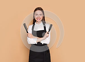 Portrait of happy hairdresser with brush and comb on beige background. Space for text