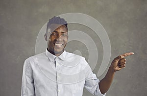 Portrait of happy handsome young black man smiling and pointing away with his finger