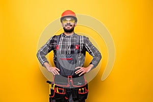 Portrait of happy handyman with tool belt isolated on yellow background