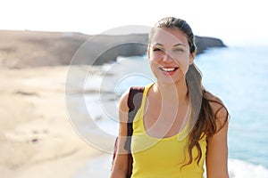 Portrait of happy hiker woman standing on the top of viewpoint looking at camera with blurred natural landscape. Travel and active