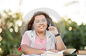 Portrait Of Happy Hispanic Student Woman Learning Sitting Outdoors