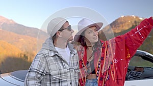 portrait of happy honeymooners travelling by car in mountains, man and woman admiring landscape