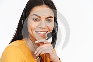 Portrait of happy hotline assistant woman wearing microphone headset speaking with customer by phone in office