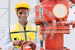 portrait happy indian engineer safety staff worker work control operate valve gas pipe oil industry