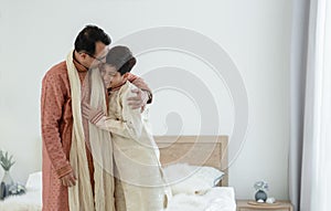 Portrait of happy Indian family standing and hugging in bedroom at home. Smart young father with little handsome son