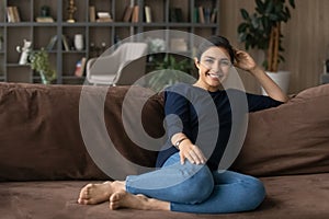 Portrait of happy Indian female renter relax on couch