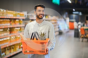 Portrait of happy Indian man standing in front of the product counter in a grocery store. Man buying grocery for home in