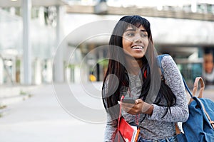 Happy Indian university student walking with mobile phone