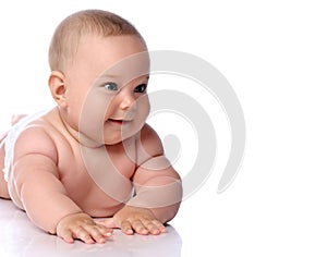 Portrait of happy infant child baby girl kid in diaper lying on her tummy, stomach looking aside at copy space
