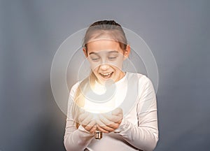 Portrait of a happy joyful child with a light bulb. The emotion of surprise