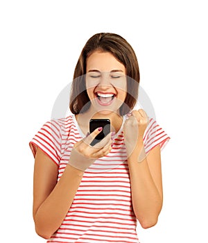 Portrait of a happy joyful girl holding mobile phone and celebrating a win. emotional girl isolated on white background