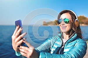 Portrait of Happy joyful woman listening to music while being outdoor. Teenage female wearing headphones having fun on a walks