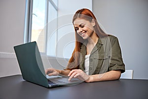 portrait of a happy, joyful woman sitting at a laptop and working in the office