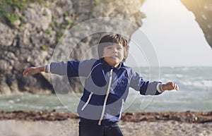 Portrait of happy kid boy smiling standing by the sea with blurry background, Chid playing in the Durdle Door beach in the weekend