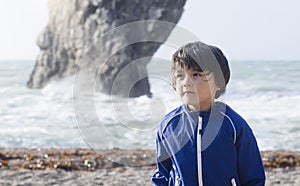 Portrait of happy kid boy smiling standing by the sea with blurry background, Chid playing in the Durdle Door beach in the weekend