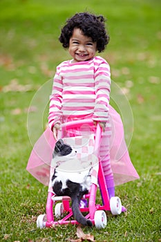 Portrait, happy kid and kitten for playing with baby carriage on grass, garden or backyard of family home. Little girl