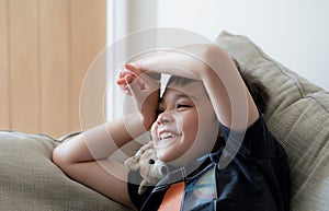 Portrait happy kid laughing, Cute little boy with big smile sitting on soafa having fun watching cartoon on TV, Positive child