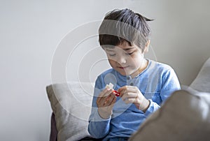 Portrait happy kid playing plastick block alone in living room, New normal life style Child boy relaxing at home on weekend.
