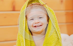 Portrait of a happy laughing baby child cover body under towel after bath. Close up positive kids face.