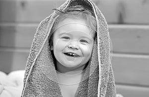 Portrait of a happy laughing baby child cover body under towel after bath. Close up positive kids face.