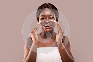 Portrait Of Happy Laughing Black Woman Applying Cream On Face