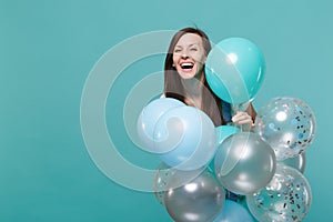 Portrait of happy laughing cute young woman in denim clothes celebrating and holding colorful air balloons isolated on