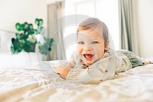 portrait of happy laughing toddler girl lying on parent`s bed