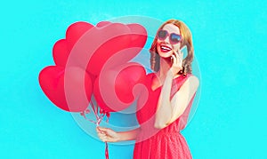 Portrait happy laughing woman calling on smartphone with pink heart shaped air balloons on colorful