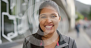 Portrait of a happy laughing woman outside in the city. Face closeup of an african sports coach or athlete smiling