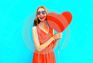 Portrait happy laughing woman in red dress, a balloon in the shape of a heart