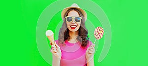 Portrait of happy laughing young woman with ice cream and lollipop wearing summer straw hat on green background