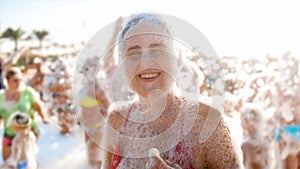 Portrait of happy laughing young woman in red bikini dancing on the sea beach. Girl having fun on sea beach soap foam